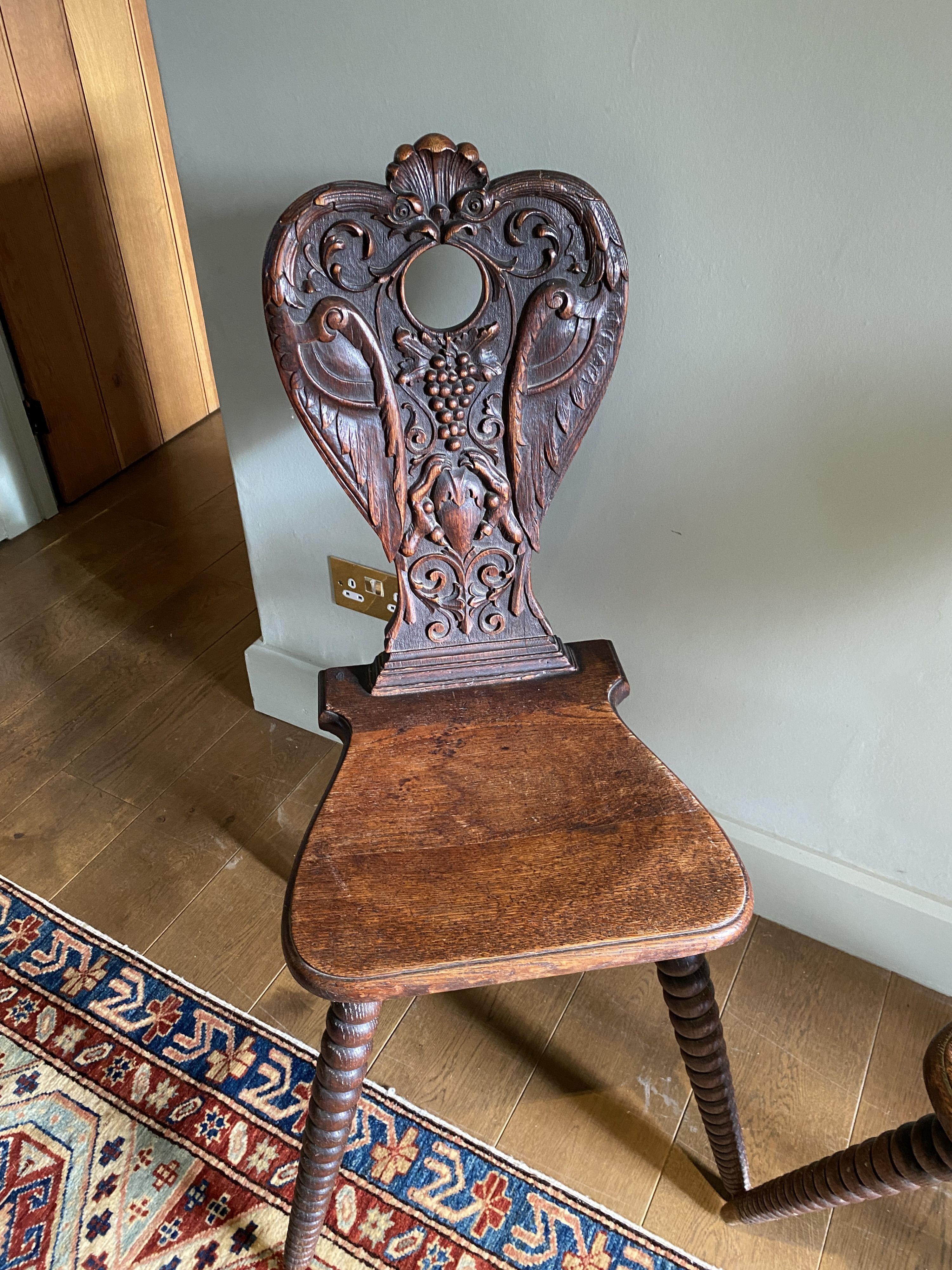 A pair of 19th century Swiss carved oak hall chairs, with vine and scroll backs and tapered bobbin turned legs, width 55cm height 98cm